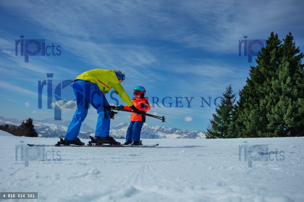 Dad show child how to ski going downhill holding poles in hands