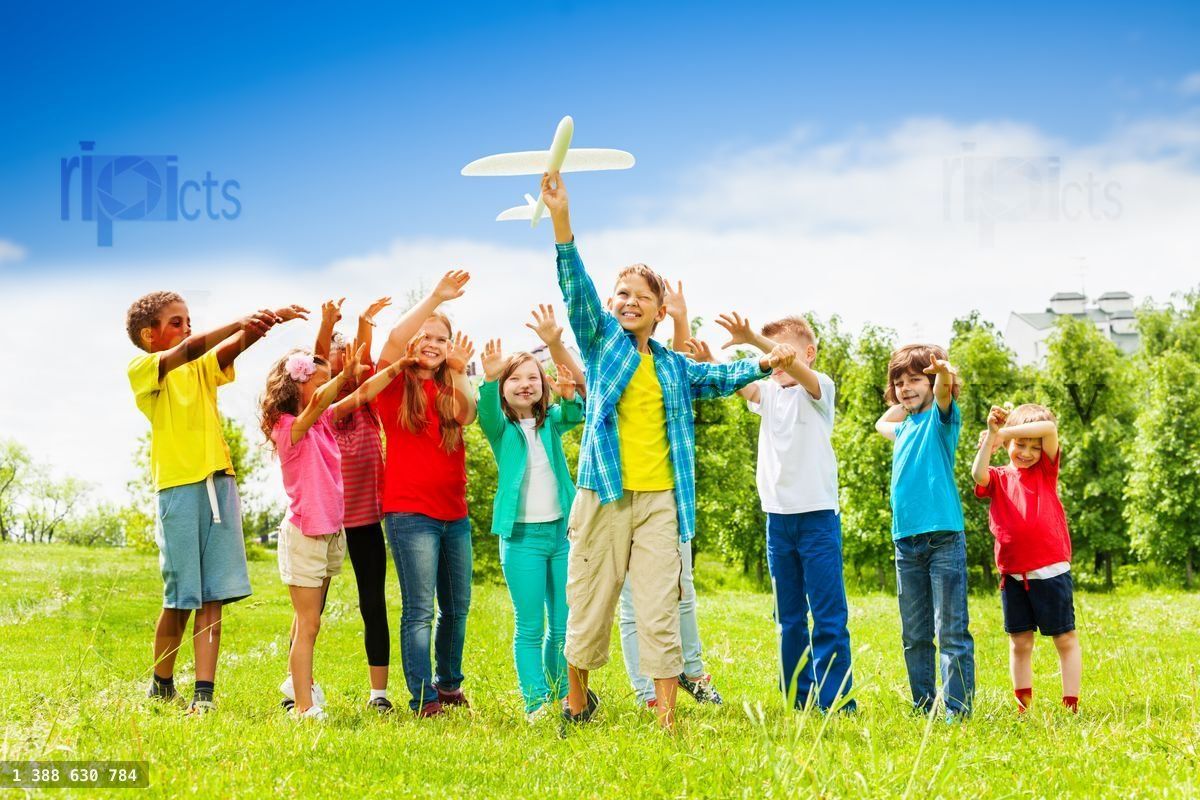 Kid holding white airplane toy and children behind