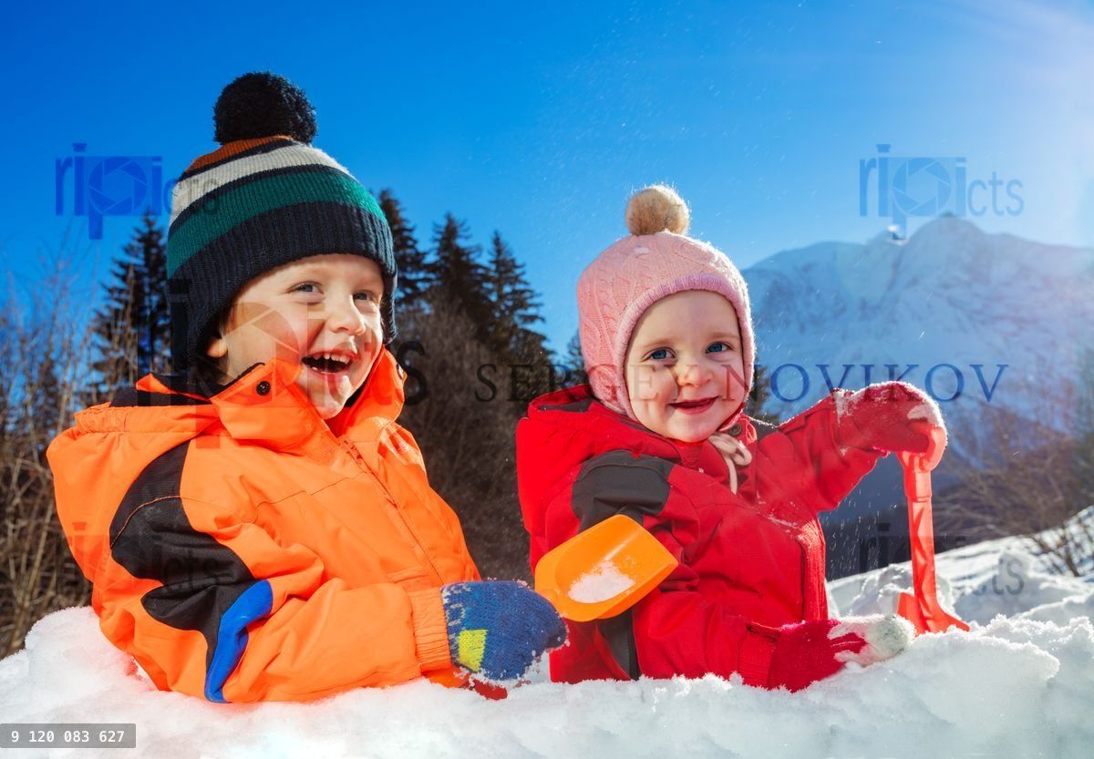 Boy with sister girl play in snow fortress on winter vacation