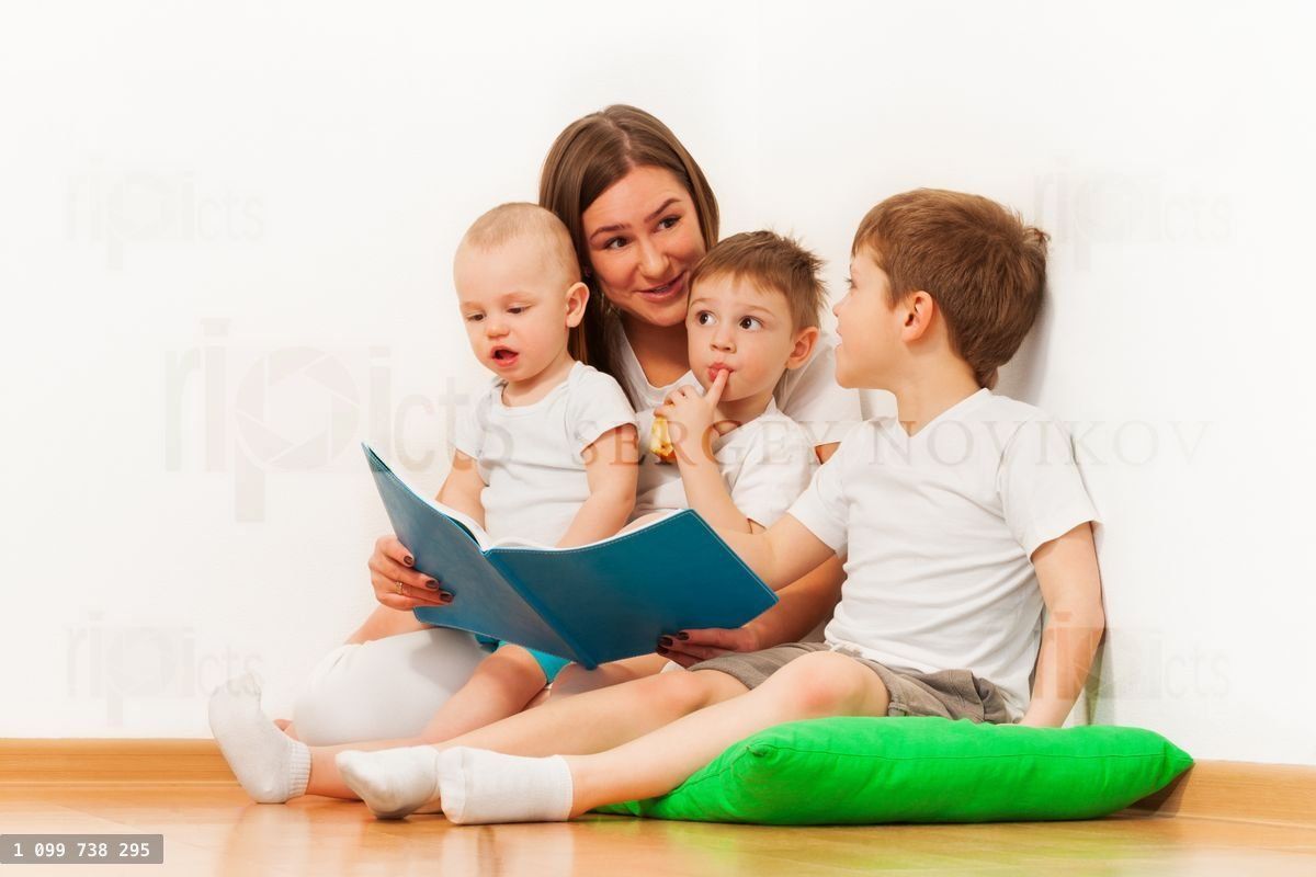 Young mother reading book to her age diverse kids
