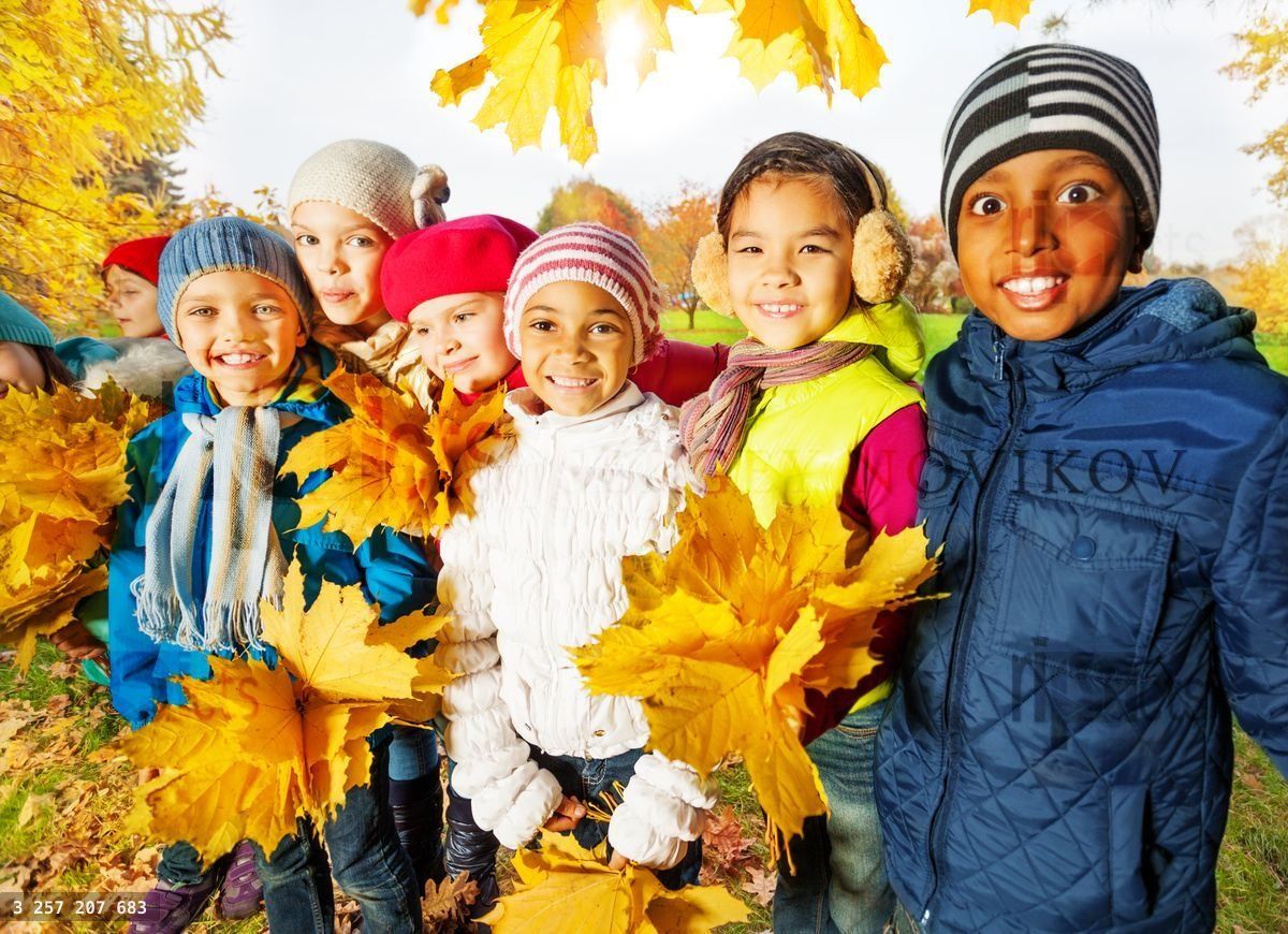 Happy children with bunches of yellow maple leaves