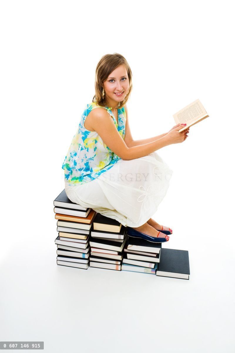 Woman reading book sitting on pile of them