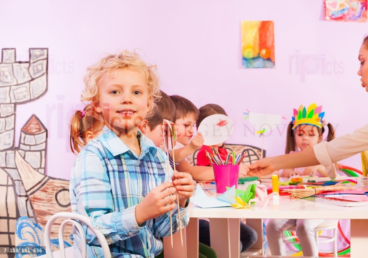 Blond boy in preschool class sit by table