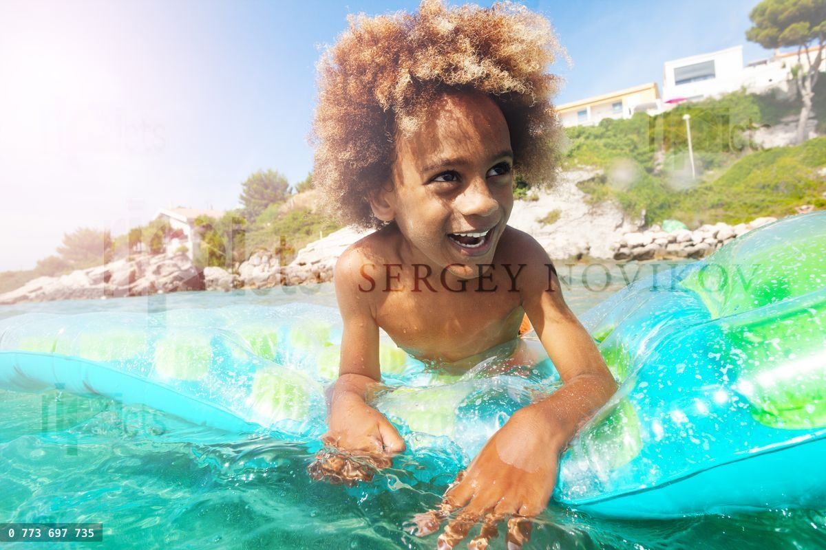 Happy African boy relaxing on swimming mattress