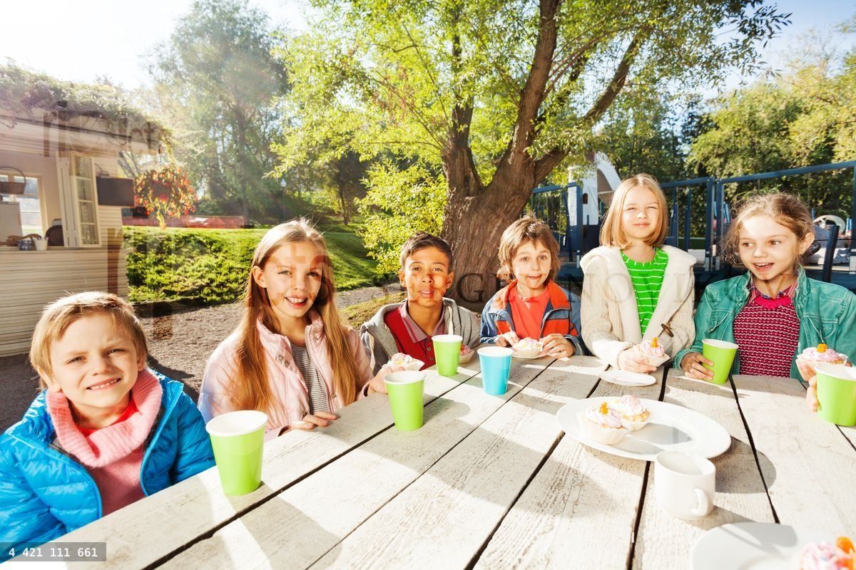 Happy group of children sitting at table outside