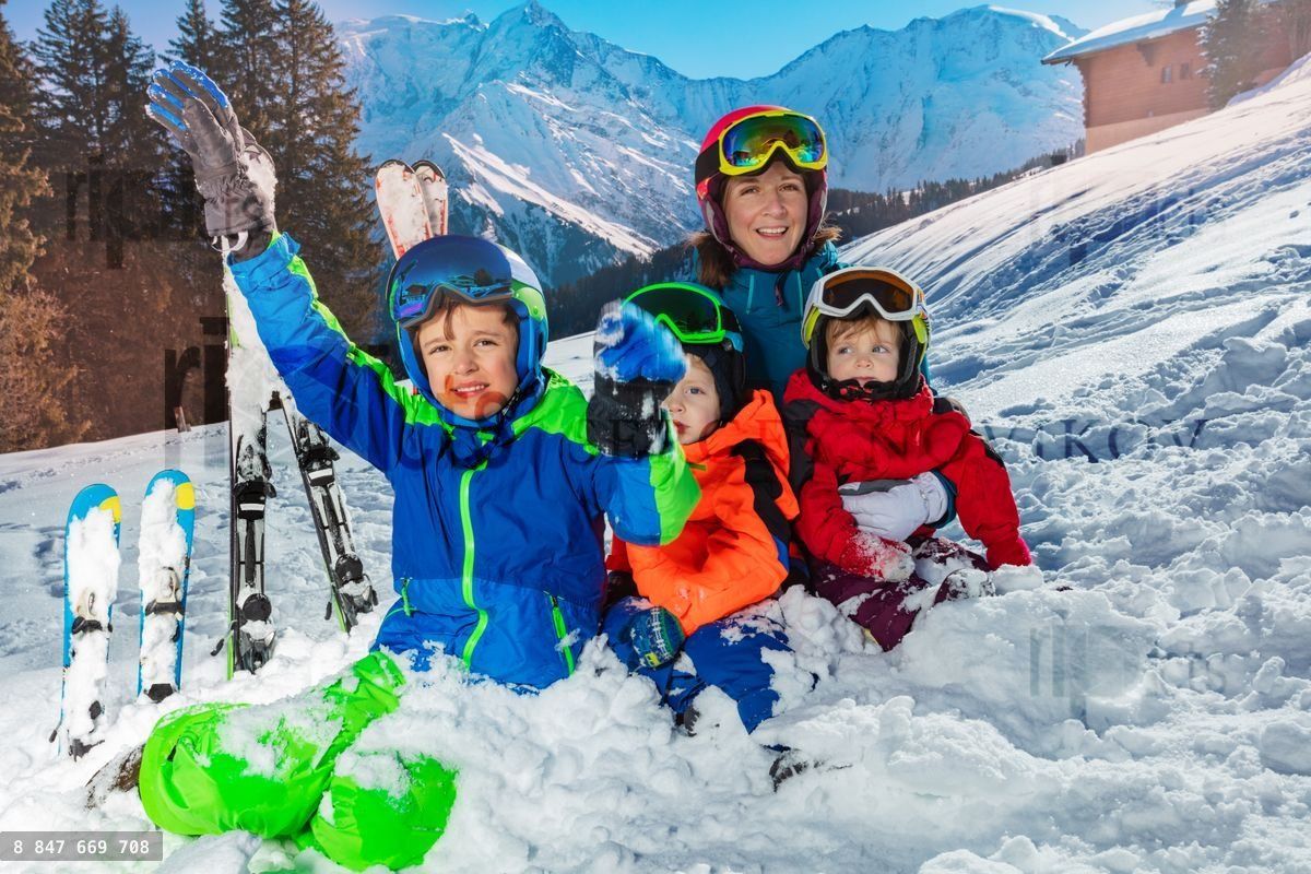 Family on ski vacation sit together in the snow over Mont Blanc
