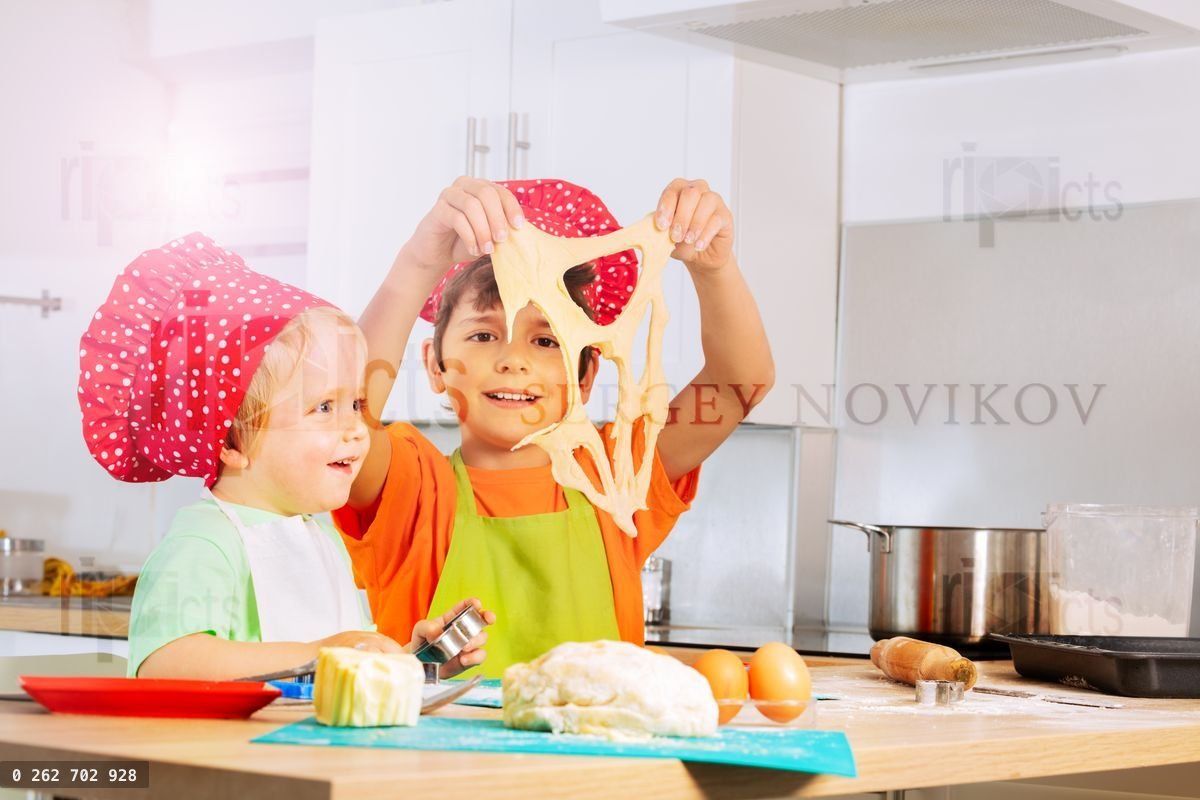 Niño sonriente jugando sosteniendo masa cortando galletas