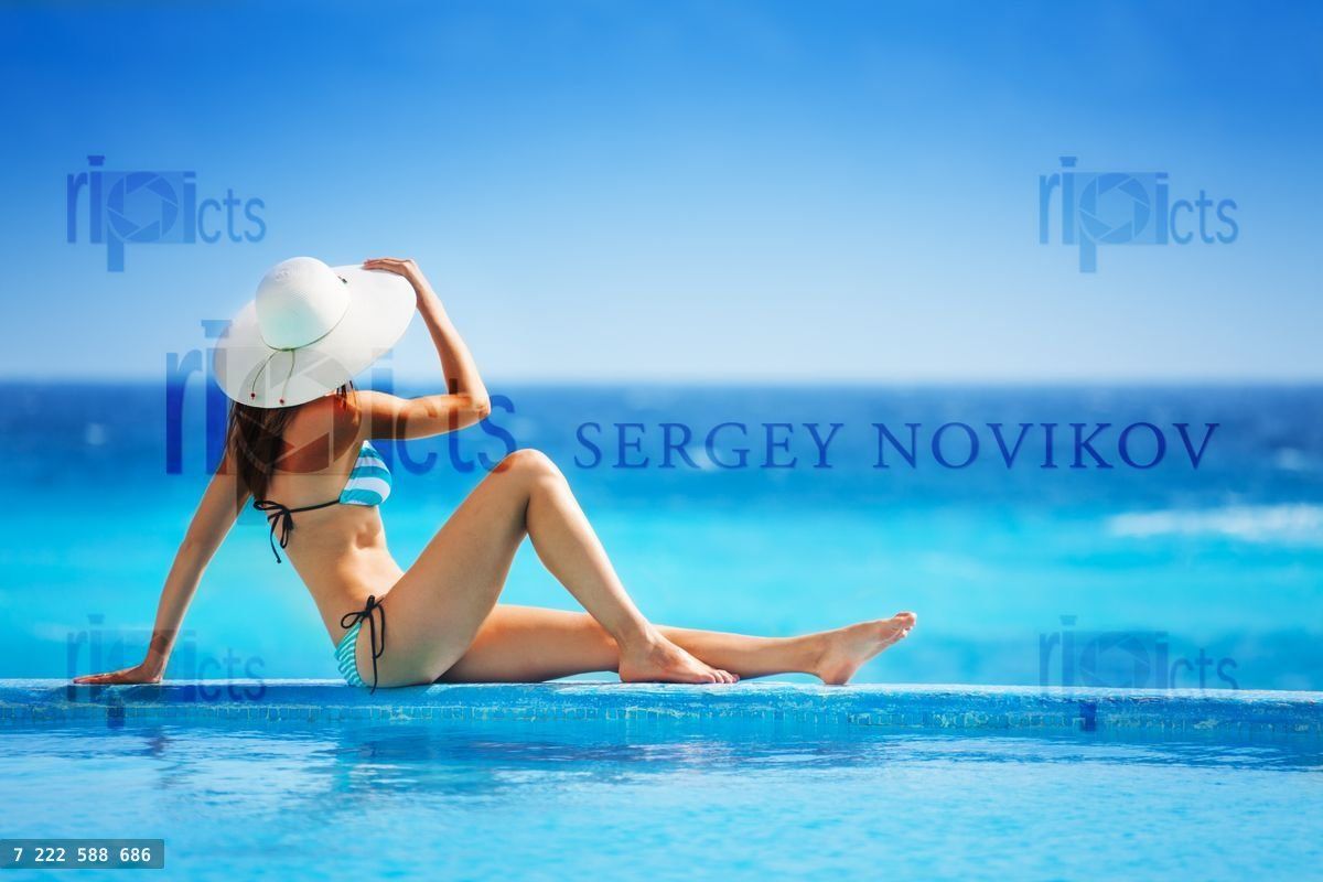 Girl from back with white hat in striped bikini