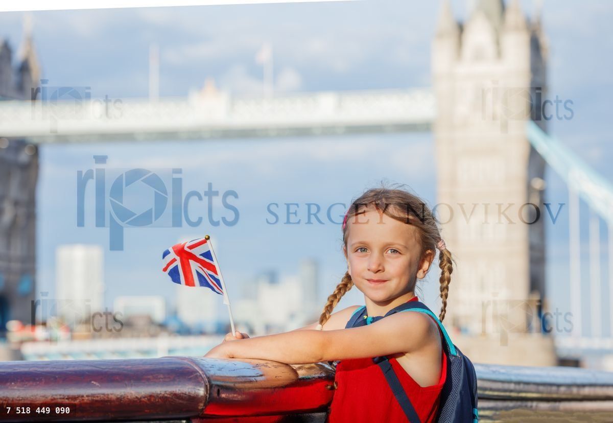 Young girl joyfully holding British flag by Tower Bridge