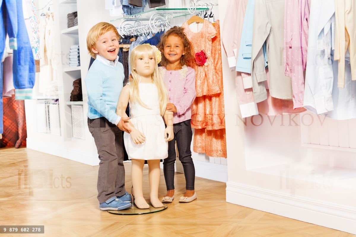 Boy and laughing girl stand with doll mannequin