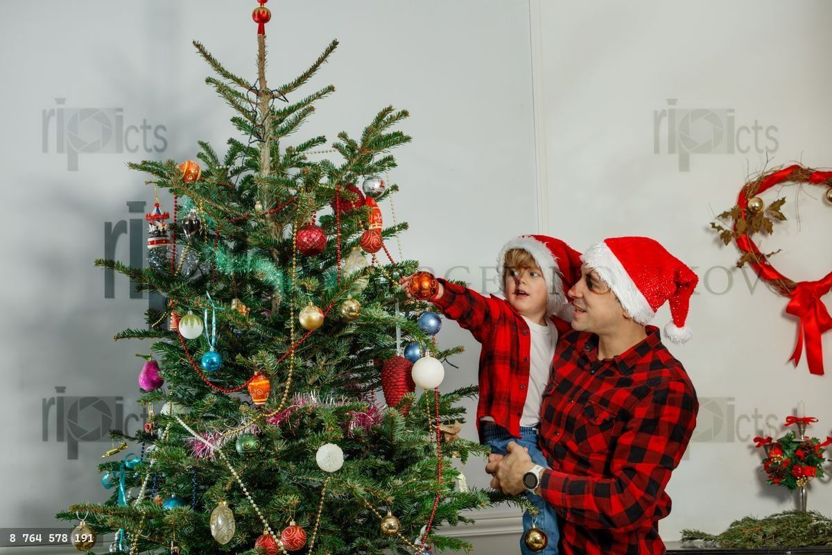 Dad and son joyfully decorating their Christmas tree together
