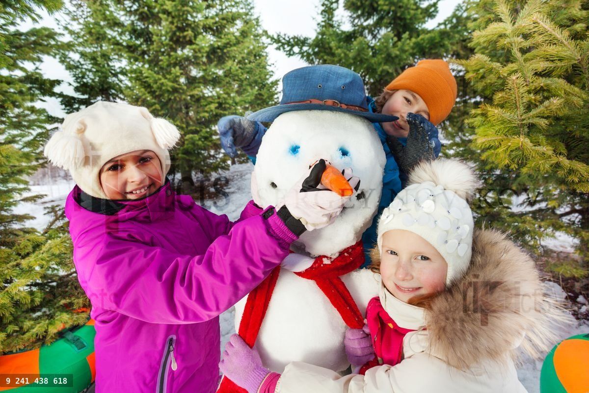Close up of happy children build cheerful snowman
