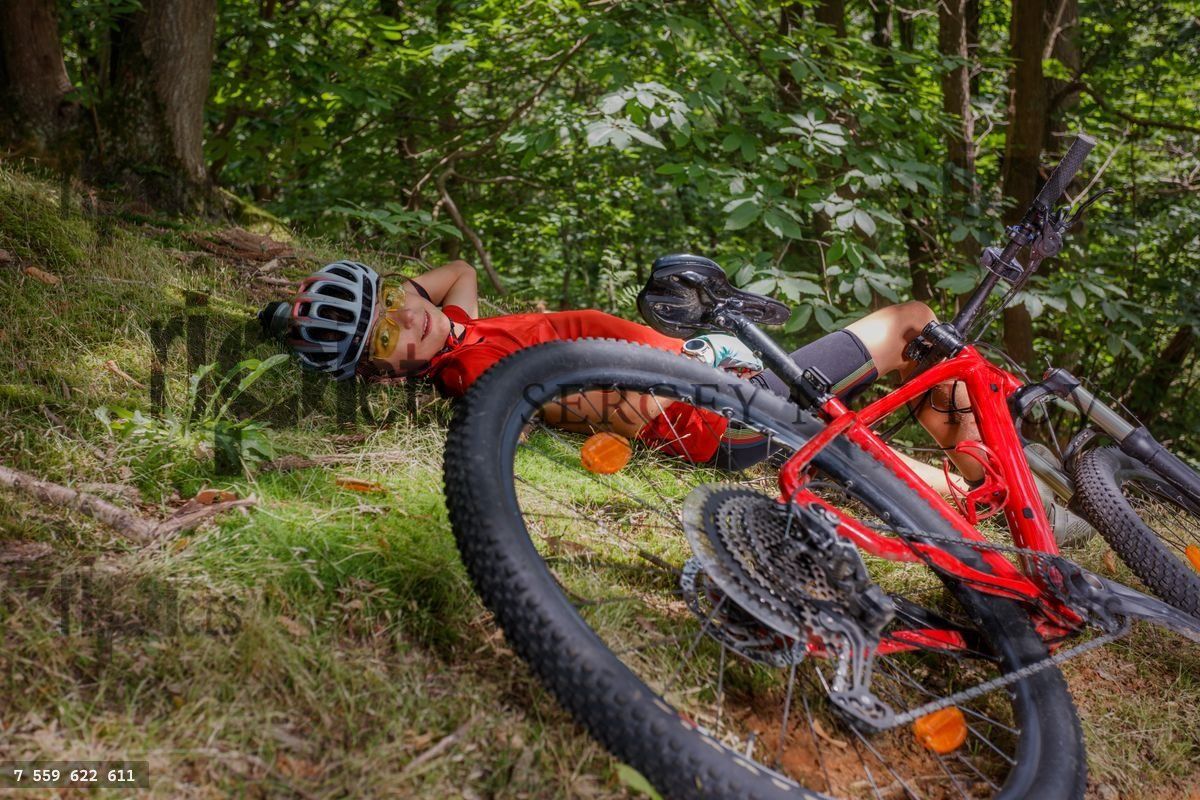 Biker in red shirt takes break lying on the grass near his bike