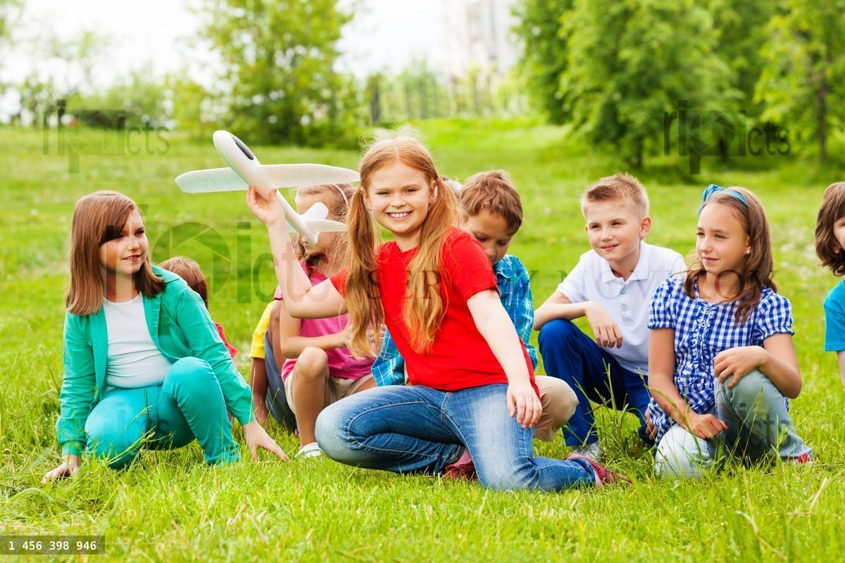 Fille tient un jouet avion et des enfants sont assis derrière