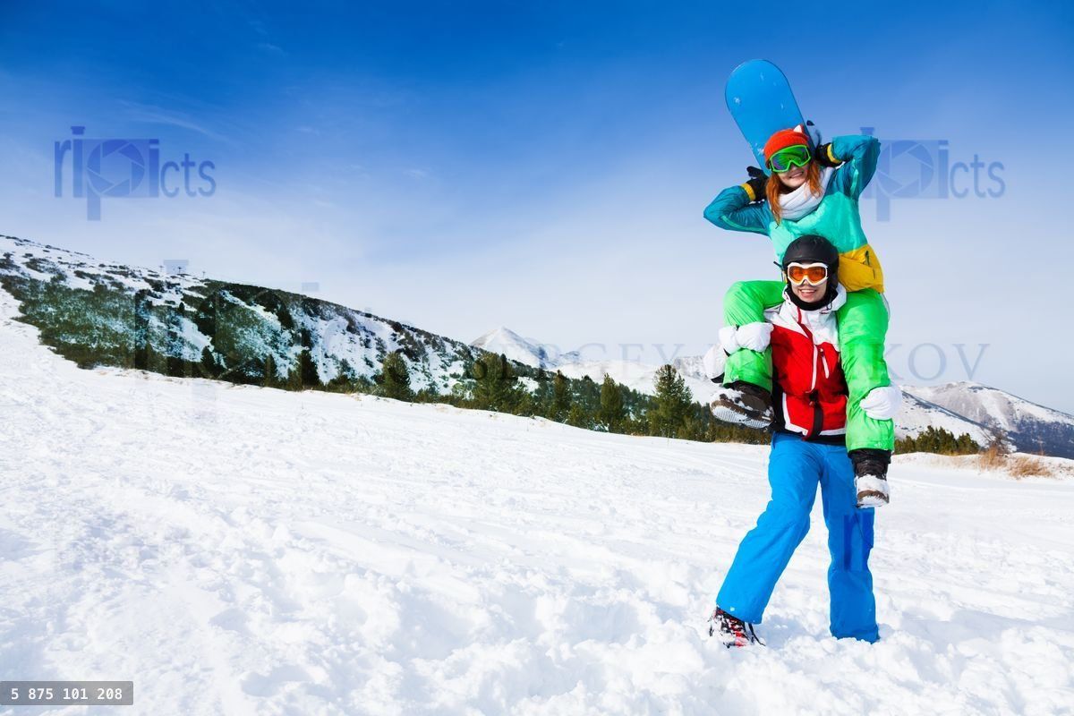 Funny snowboarder holding girl on his shoulders