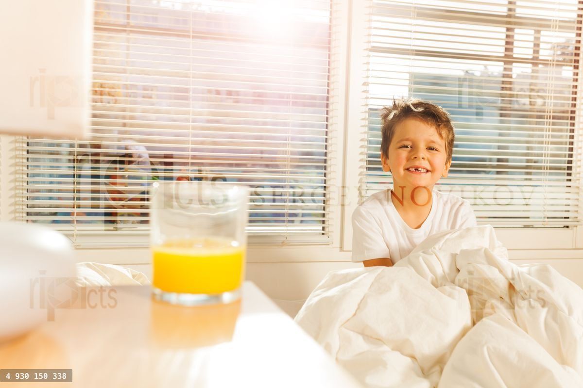 Happy boy starting his morning with glass of juice