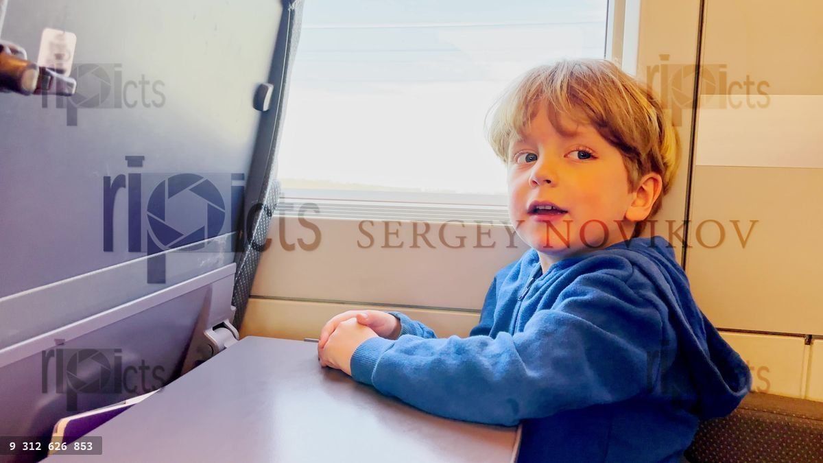 Young boy gazing out train window on a journey, happy traveler