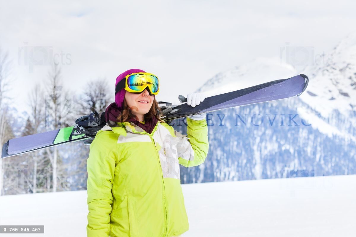 Beautiful woman in mask standing and holding ski