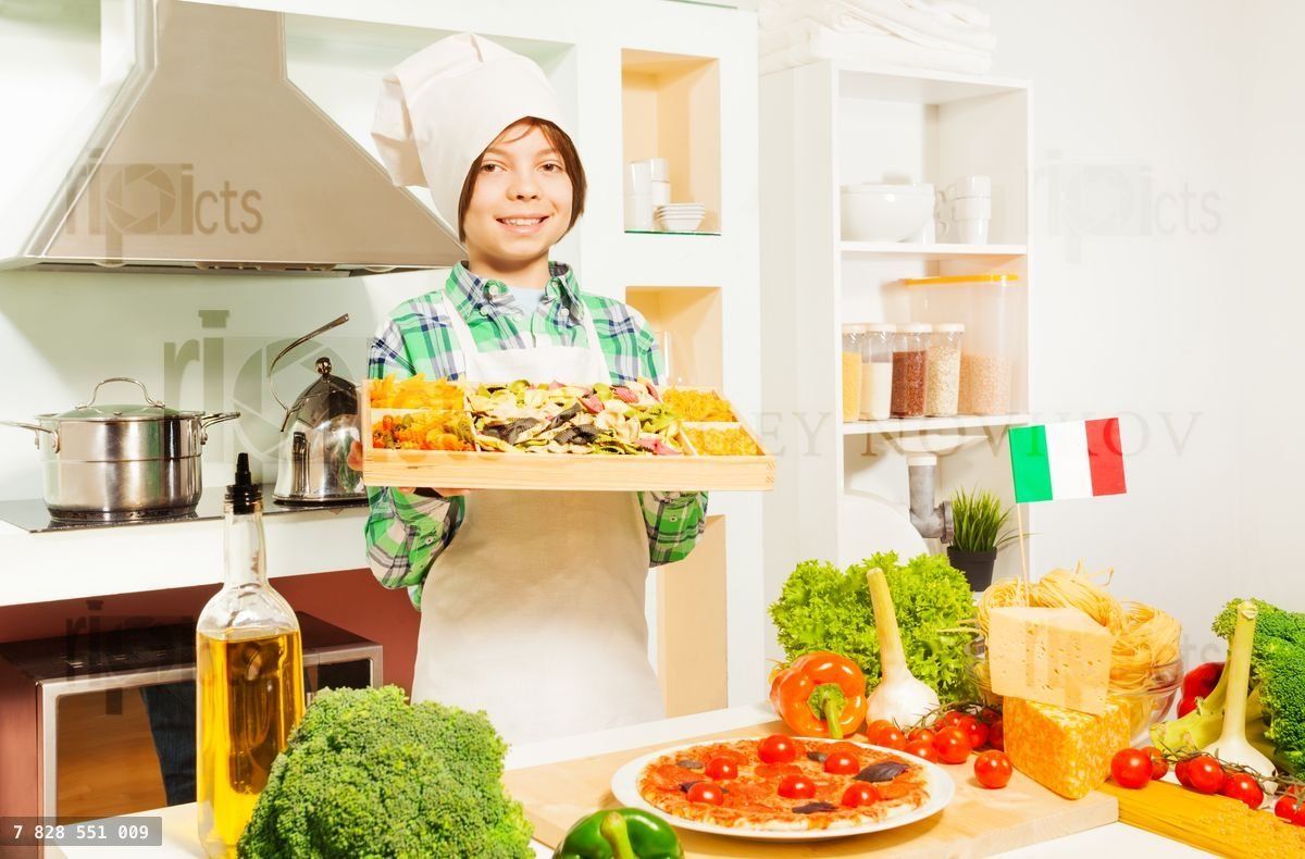 Young cook holding tray with mix of Italian pasta