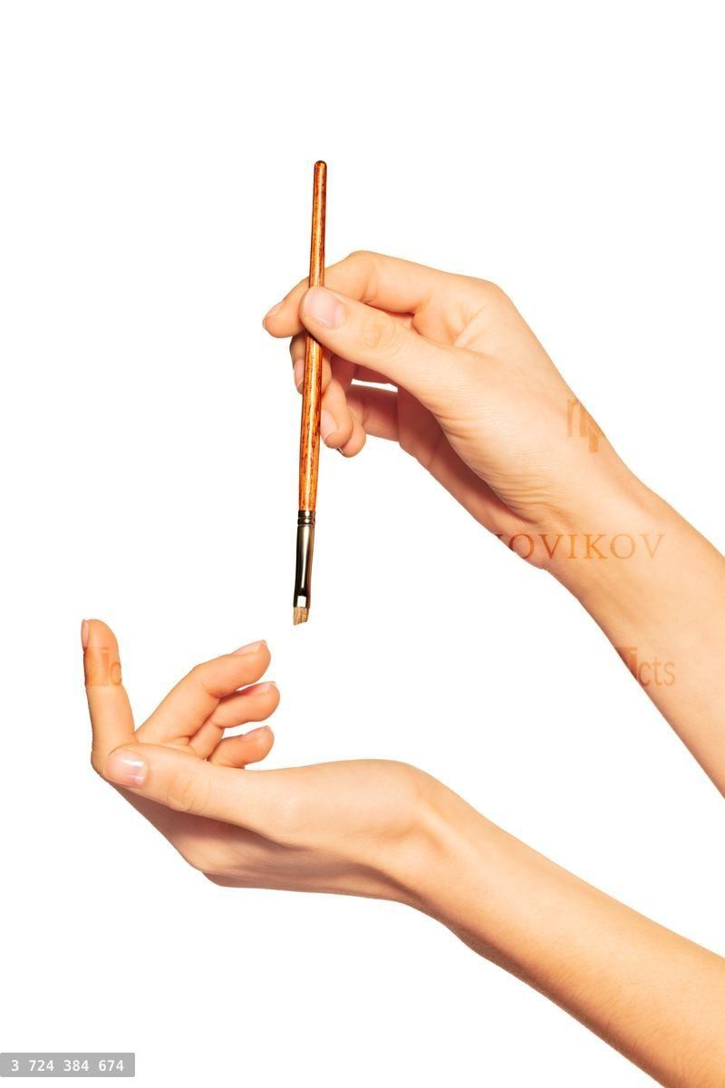 Woman's hand holding angled eyebrow brush on white