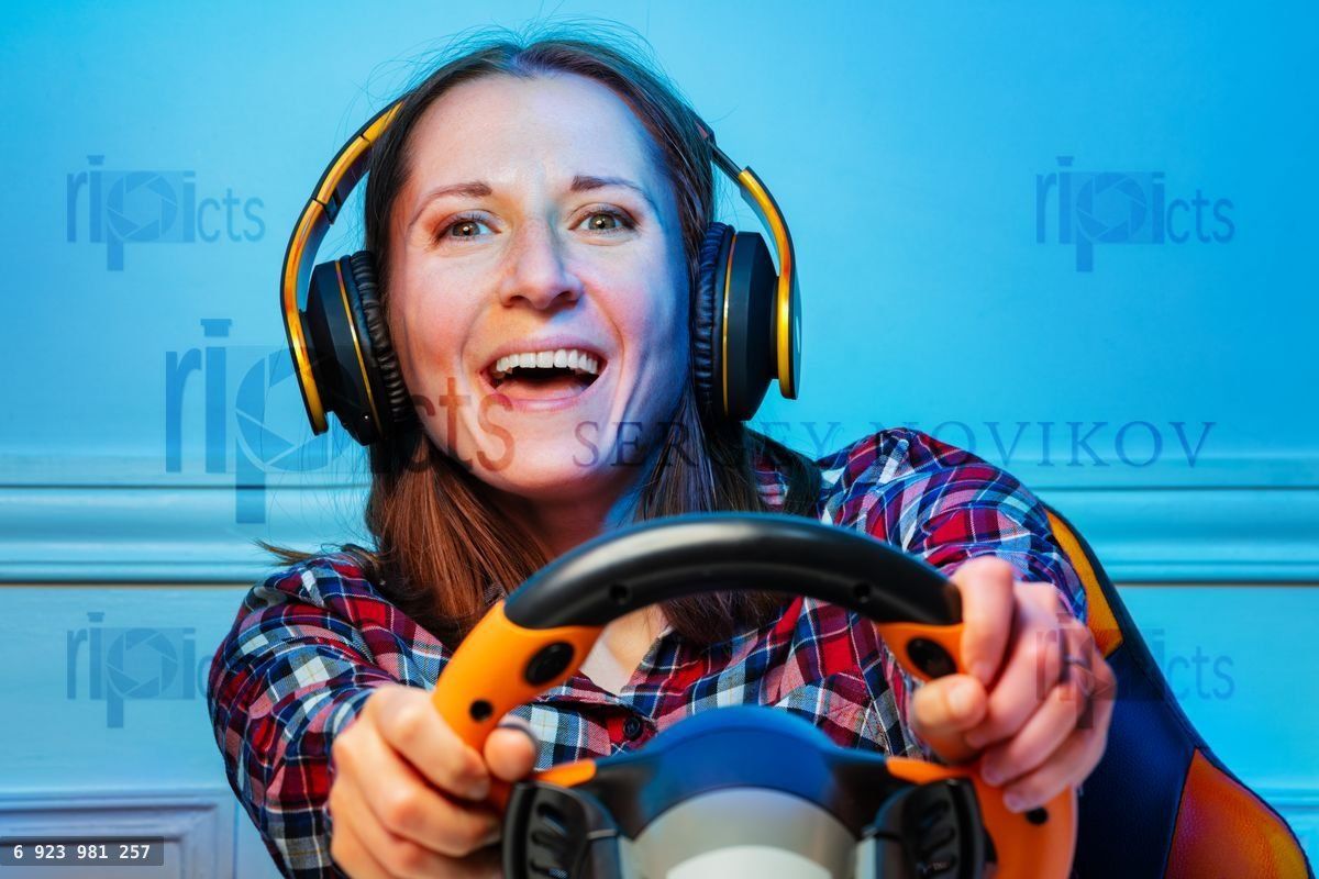 Gamer woman in headphones with hands on console steering wheel