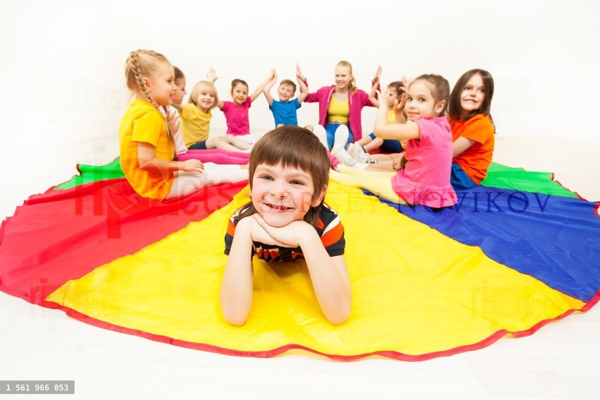 Happy boy laying on parachute during social games