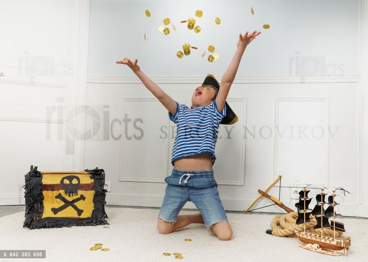 Young pirate kneels tossing coins beside a small treasure chest