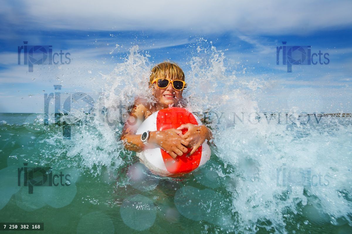 Fun in the sea boy with sunglasses and color inflatable ball