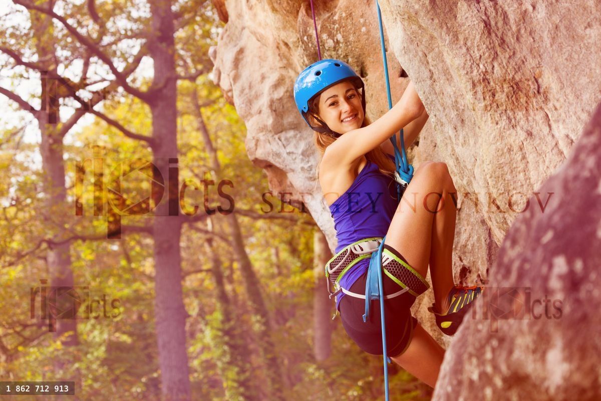 Young alpinist girl climbing on a mountain rock
