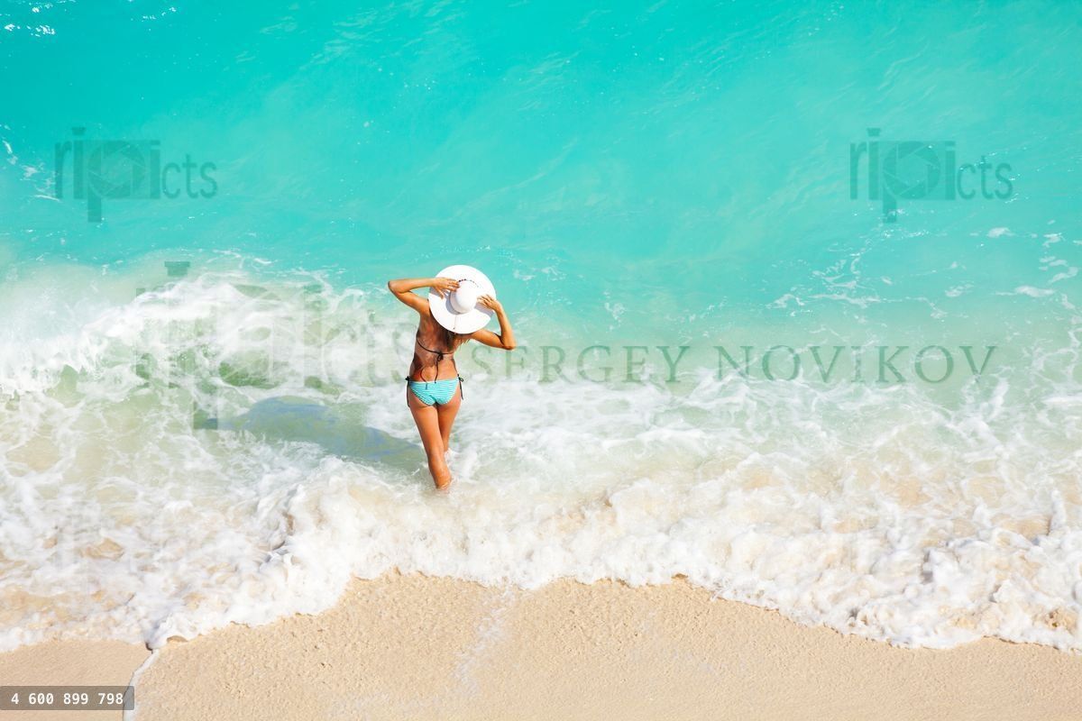 Young woman from back with white hat on the beach
