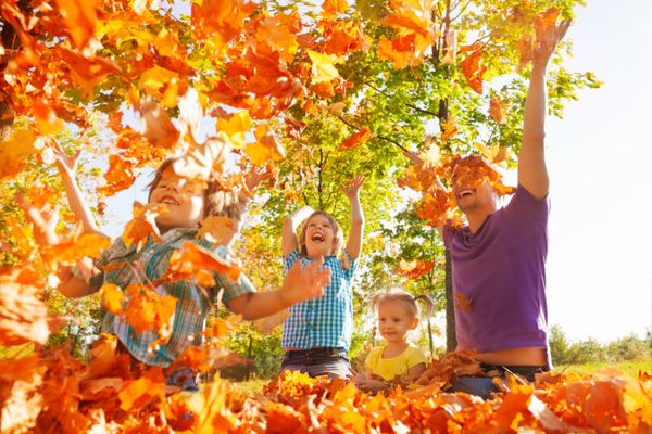 Happy family throwing leaves in air while sitting