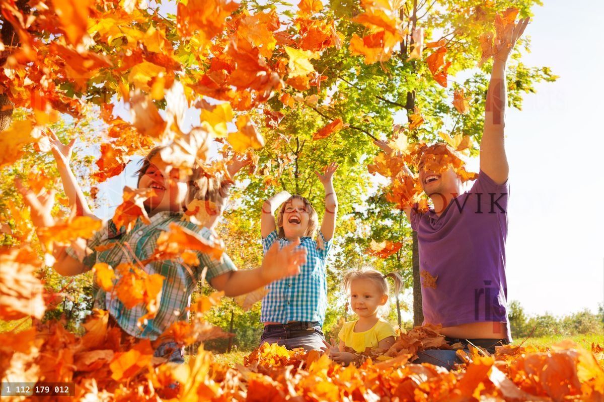 Happy family throwing leaves in air while sitting