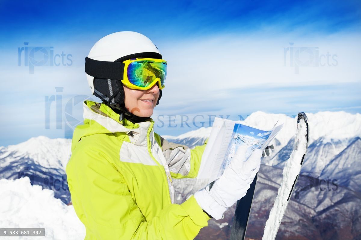 Woman with map of ski tracks on the mountain peak