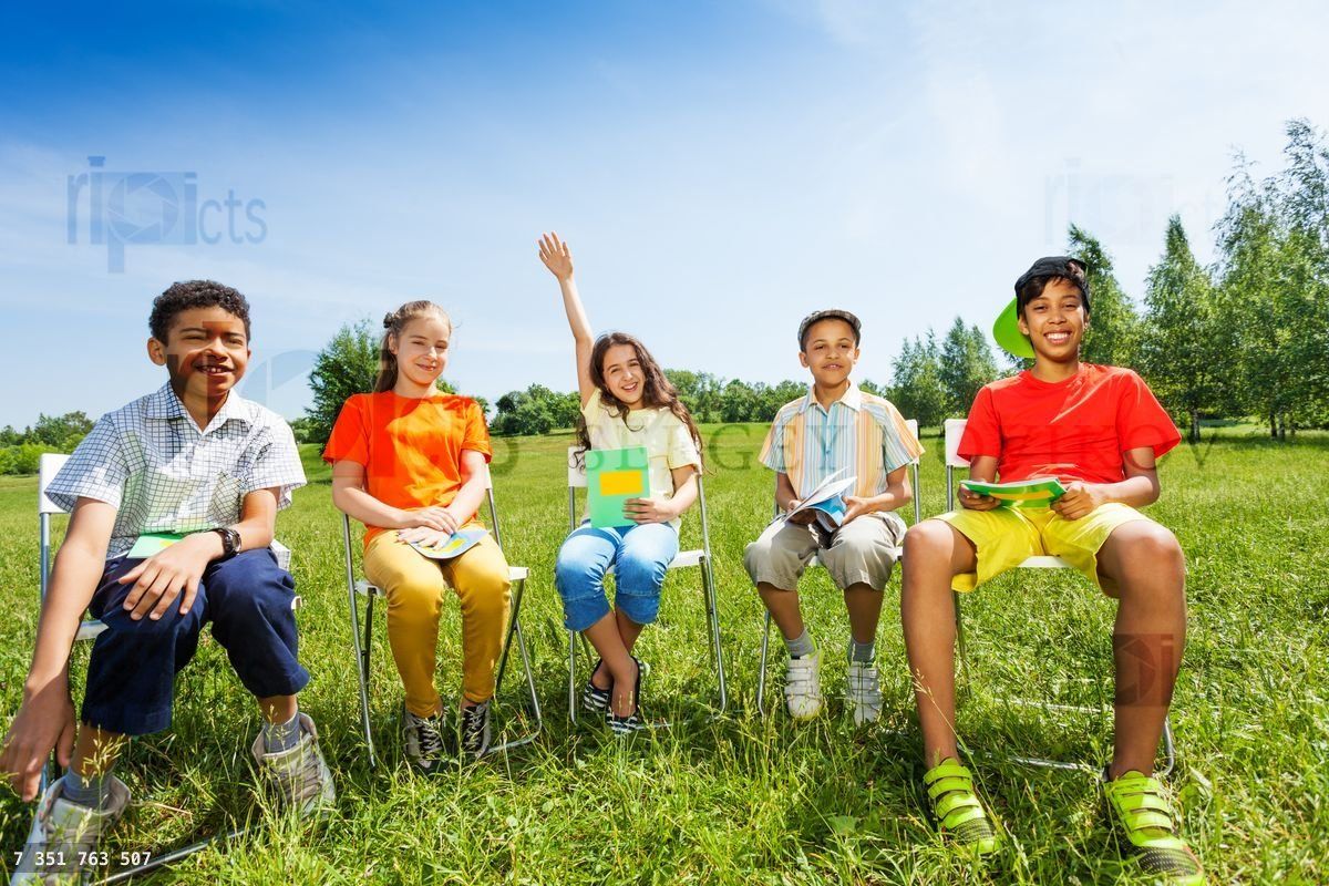 Friends sitting in row with one girl raising hand