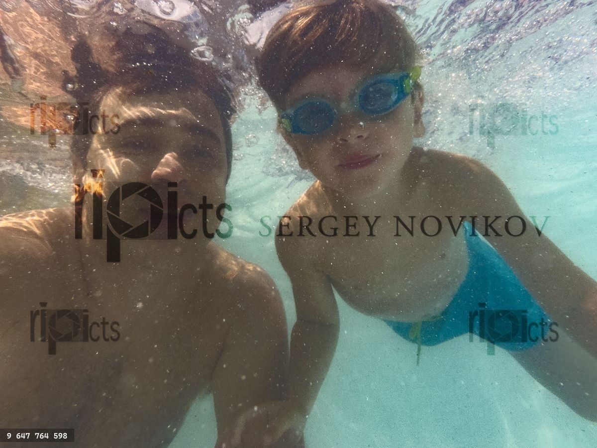 Fun underwater selfie of father and his son at swimming pool