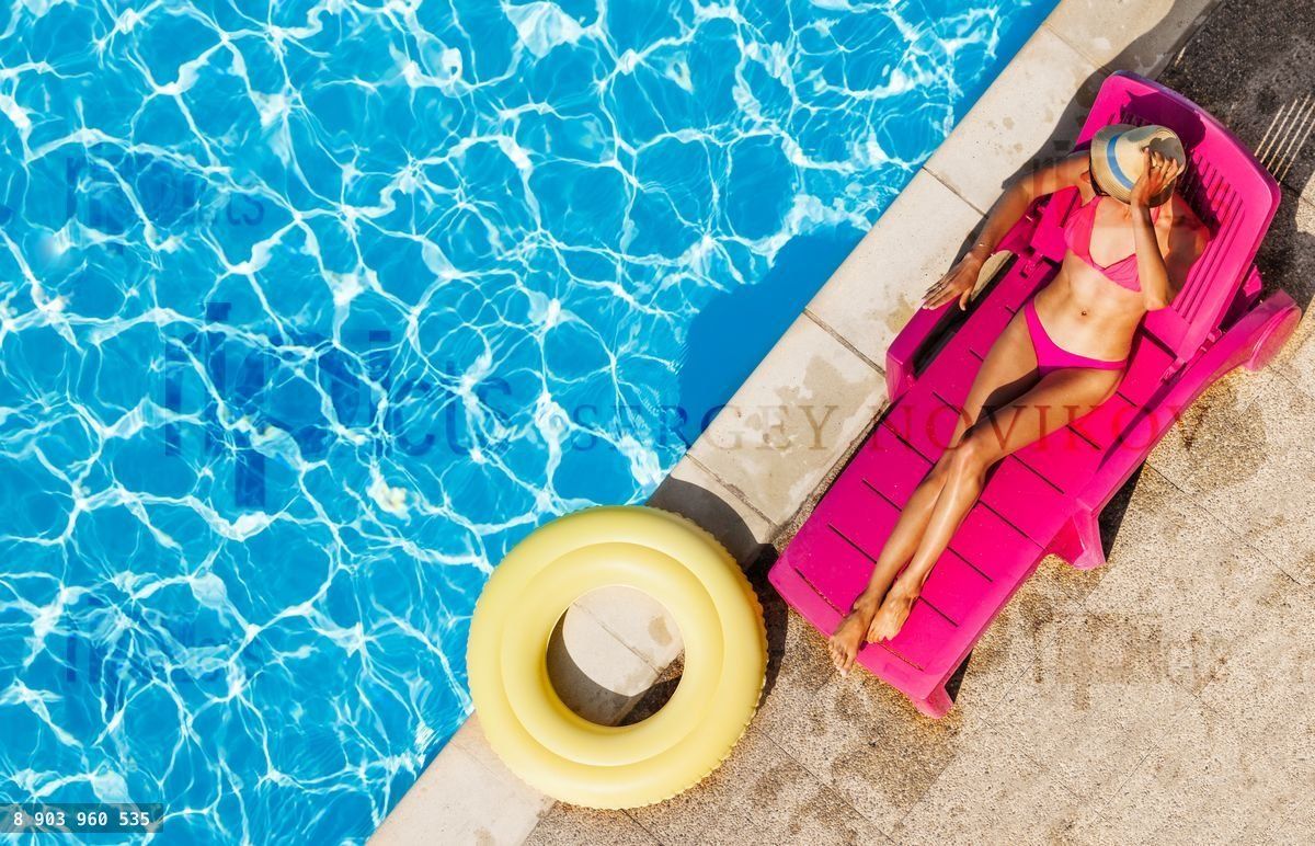Woman relaxing on chaise lounge by swimming pool
