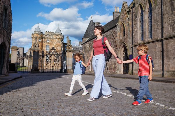 Leisurely family walk beside ancient castle entrance in Edinburg