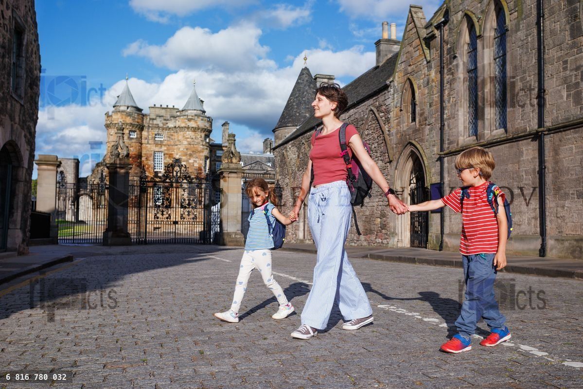 Leisurely family walk beside ancient castle entrance in Edinburg