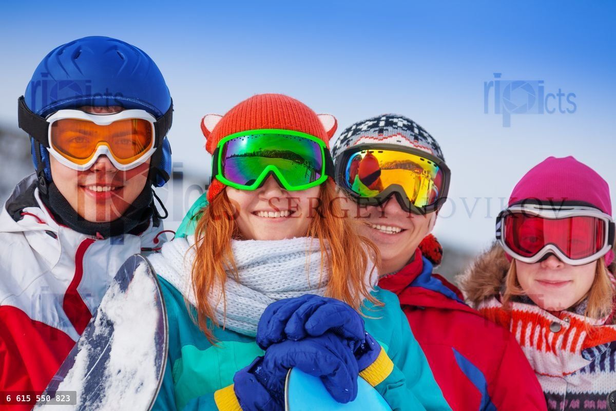 Four happy snowboarders wearing goggles