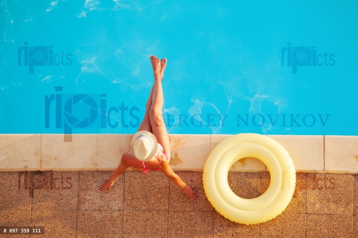 Woman in straw hat with rubber ring by the pool