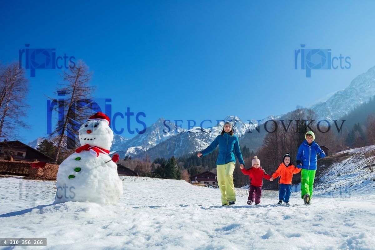 Family with kids enjoys scenic Alpine walk in winter resort