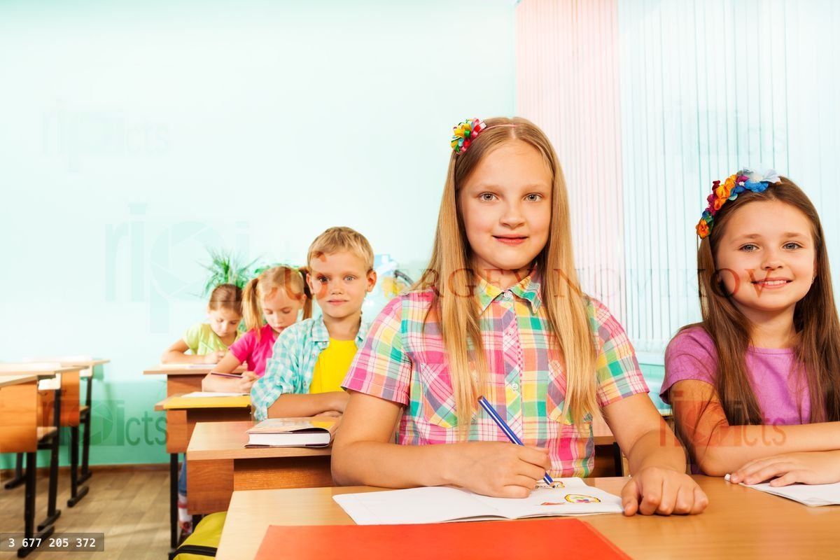 Writing girl looking straight and sitting at desk