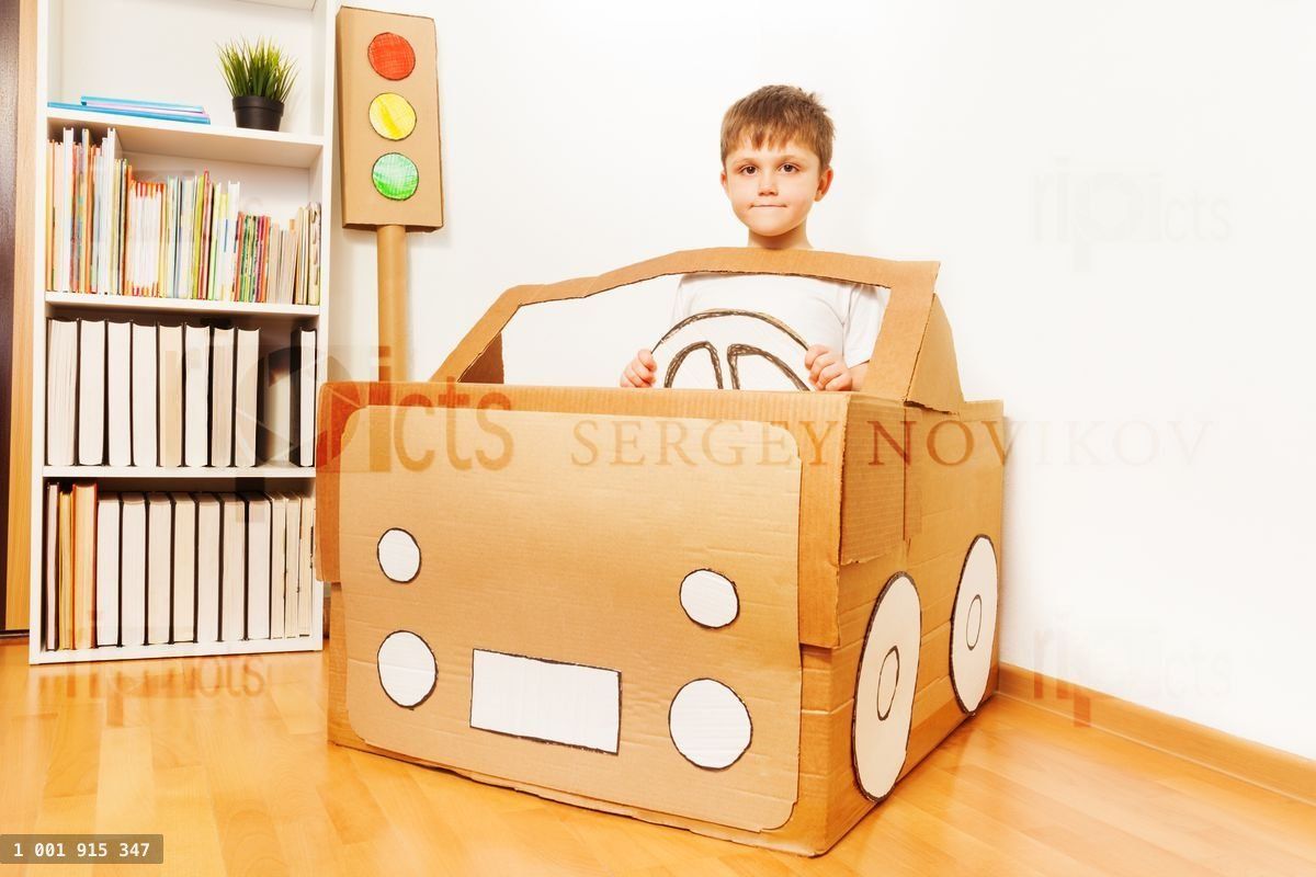 Creative kid boy plays with his cardboard car