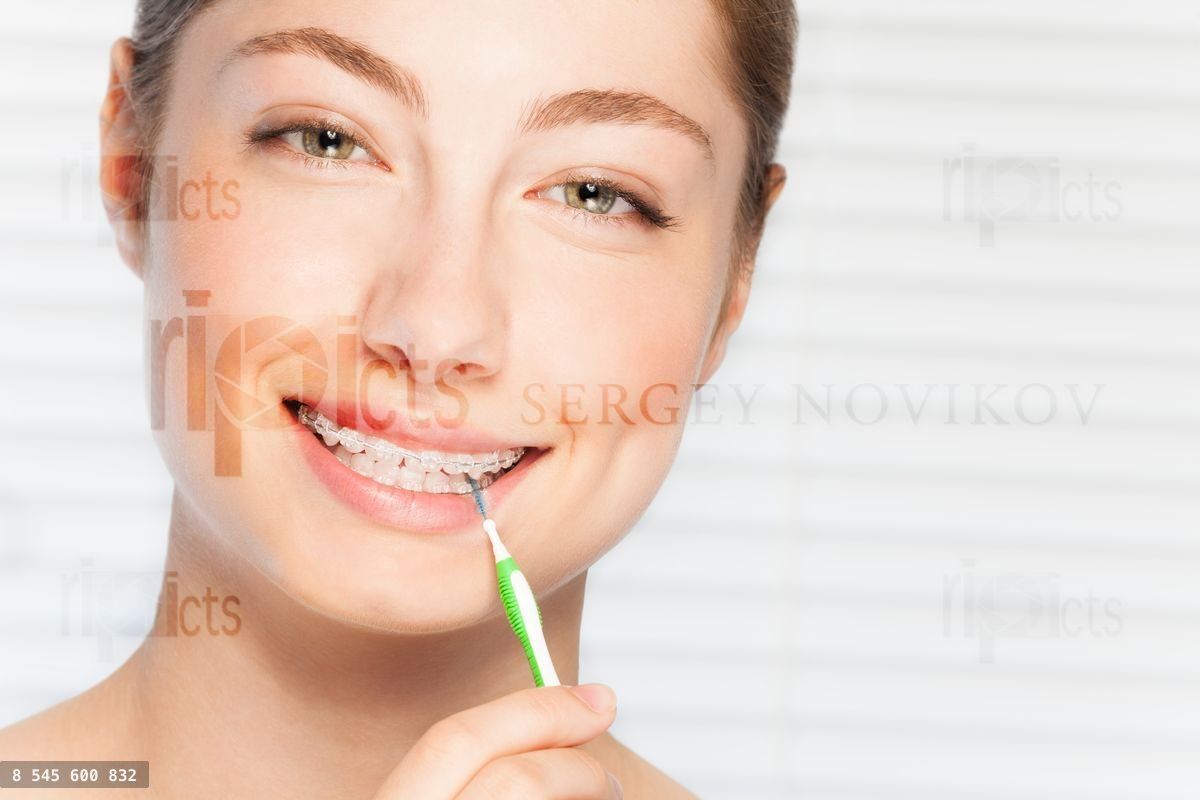 Woman cleaning teeth brace by interdental brush