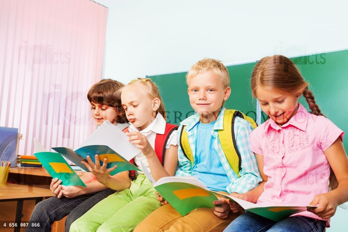 Four schoolchildren sit in row on desk and read