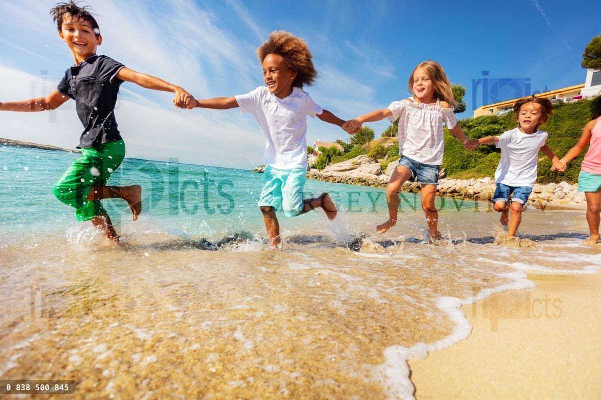 Friends holding hands and running along the beach