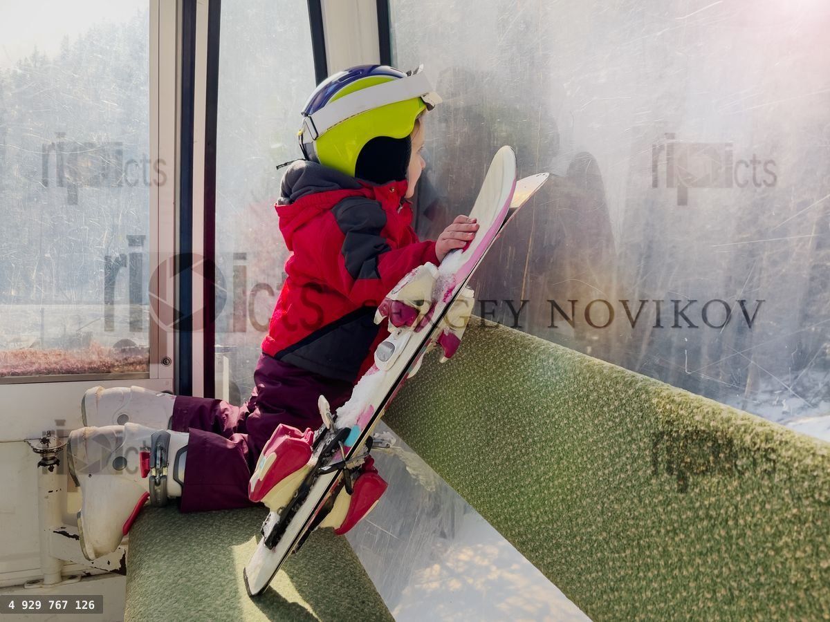 Young skier in cable car observing ski slops getting to the top