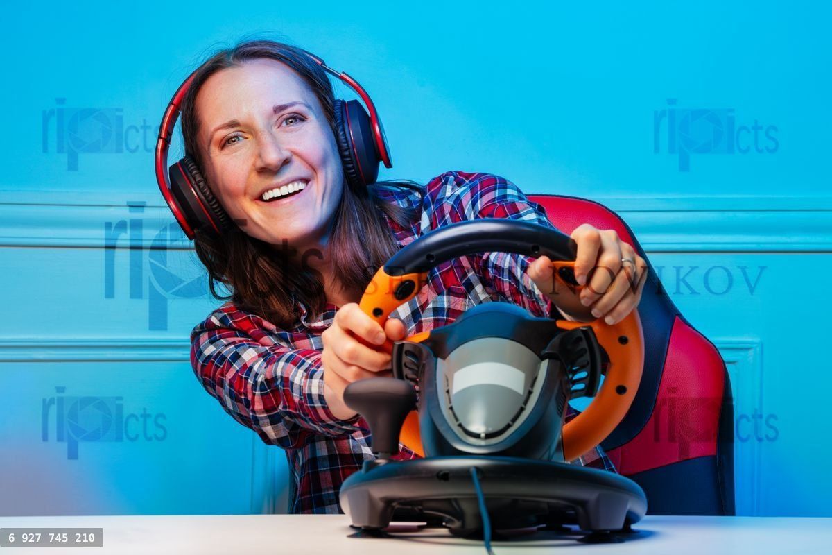 Gamer woman in headphones playing race game with steering wheel