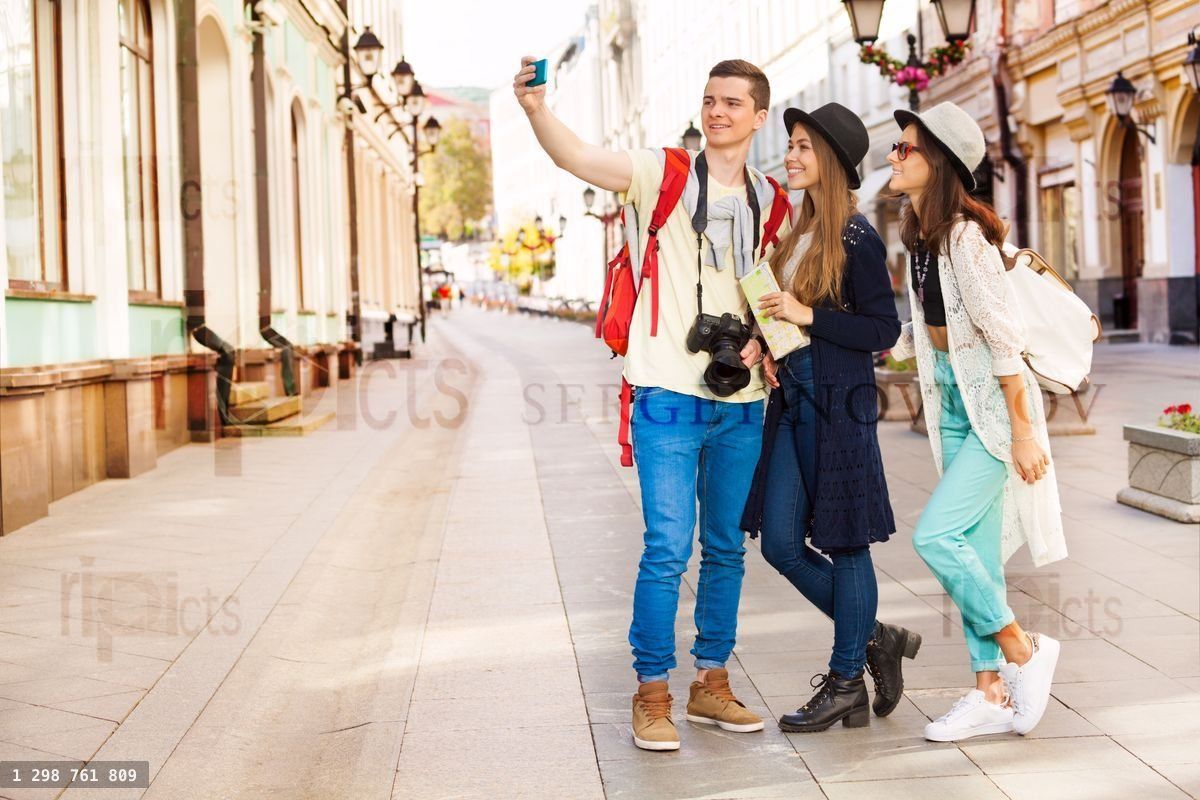 Guy and two girls taking selfies with mobile phone