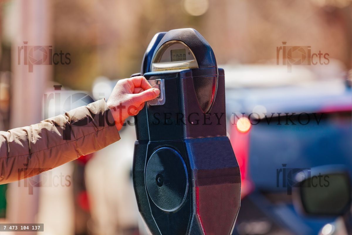 Woman pay on street parking meter pole with coin